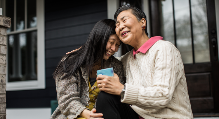 Mother and daughter laughing together on a porch